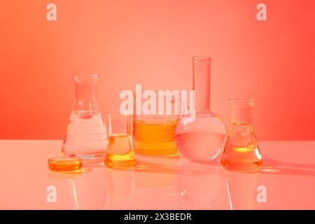 Concept de recherche scientifique avec de nombreux types de verrerie de laboratoire remplis de liquide orange. Expérience de laboratoire et recherche Banque D'Images