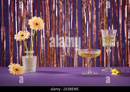 Un pot de fleurs décoré sur une table violette avec des verres à vin. Vue de face. Espace vide au milieu pour la promotion du produit. Concept de fête de vacances Banque D'Images