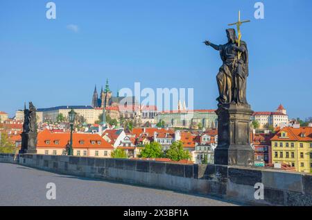 Statue de St. Jean-Baptiste sur le pont Charles, avec le château de Hradcany et St. Cathédrale de Vitus en arrière-plan, à Prague, République tchèque, sous le soleil Banque D'Images