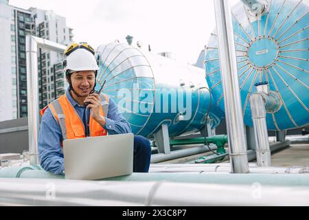 ingénieur technicien masculin travaillant le service commercial bâtiment commercial systèmes d'approvisionnement en eau chaude de pompe à chaleur. sécurité de l'homme vérifiant l'entretien de l'eau de chauffage Banque D'Images