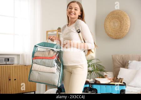 Jeune femme enceinte avec des sacs prêts pour les vacances dans la chambre Banque D'Images