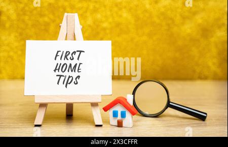 Premier concept de conseils à la maison. Des conseils et des conseils destinés aux personnes qui achètent leur première maison. Maison miniature et loupe Banque D'Images