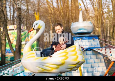Heureux papa et fils roulent sur les attractions dans un parc de la ville par une journée ensoleillée. Passer du temps en famille. S'amuser ensemble Banque D'Images