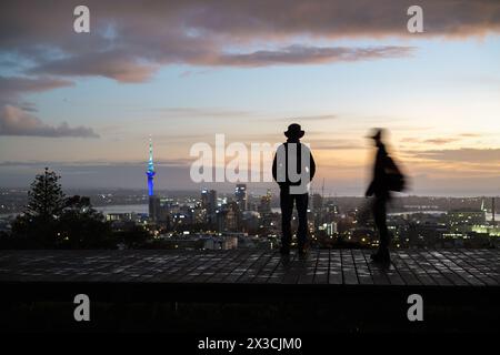 Les gens en silhouette marchant sur la promenade. Sky Tower et paysage urbain au loin. Flou de mouvement grâce à une vitesse d'obturation lente. Sommet du Mont Eden à l'aube. AUC Banque D'Images