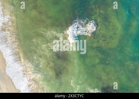 vue aérienne par drone aérienne d'une plage avec de l'eau turquoise et un rocher près de la rive Banque D'Images