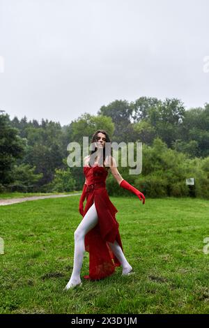 Une jeune femme attrayante dans une robe rouge et de longs gants profite de la brise estivale dans un champ serein. Banque D'Images