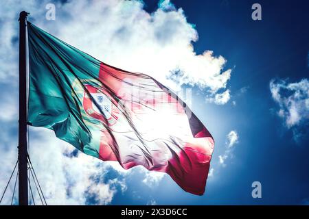 Les couleurs vives du drapeau portugais ondulent dans la brise, fièrement affichées sur une toile de fond saisissante d'un ciel bleu clair Banque D'Images