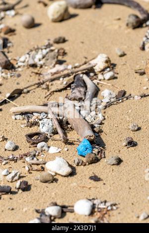 Un petit morceau de plastique bleu arrosé de pierres ponces et de bois flotté sur Mission Beach dans l'extrême nord du Queensland, en Australie Banque D'Images