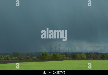 Wetter 25.04.2024, Erfurt, Blick ueber ein Feld in Richtung eines Regengebiets, der Himmel ist dunkel, Regen faellt, die Windraeder im Windpark sind durch den starken Regen kaum zu sehen *** Météo 25 04 2024, Erfurt, vue sur un champ en direction d'une zone pluvieuse, le ciel est sombre, la pluie tombe, les éoliennes du parc éolien sont à peine visibles en raison des fortes pluies Banque D'Images