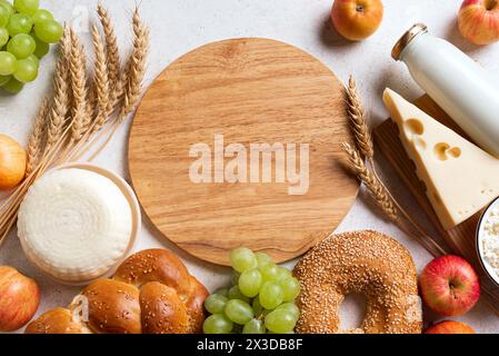 Fête juive religieuse fond de Shavuot avec produits laitiers, fromage, pain, cultures de blé et planche de bois ronde pour le texte, espace de copie. Joyeux Shavuot Banque D'Images