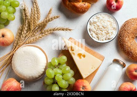 Concept de fête juive religieuse Shavuot avec des produits laitiers, du fromage, du pain, du lait, des cultures de blé et des fruits sur fond blanc. Joyeux Shavuot. Banque D'Images