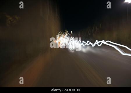 Les feux de circulation traînent en mouvement sur une route tranquille à Ely, Cambridgeshire, Royaume-Uni la nuit Banque D'Images