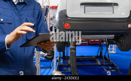 Technicien de service avec tablette numérique sur le fond de la voiture dans le service de voiture Banque D'Images