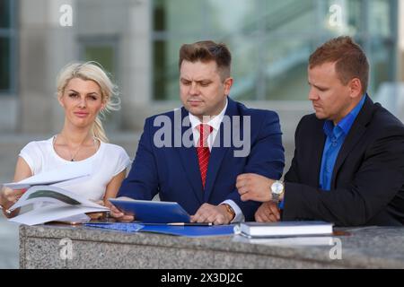 Image de l'équipe d'affaires amicale, deux homme et femme, discuter du projet, l'homme en cravate regarde la tablette Banque D'Images