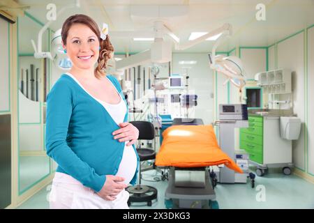 Collage avec une femme enceinte souriante en salle d'opération. Lampes spéciales, moniteur et bureau Banque D'Images