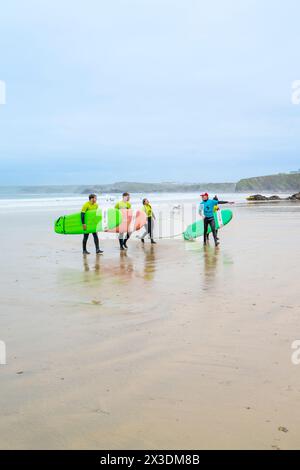 Un instructeur de surf de l'Escape Surf School marchant avec un groupe de surfeurs débutants sur la plage de Towan à Newquay en Cornouailles au Royaume-Uni. Banque D'Images