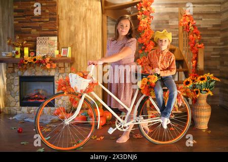 Portrait de mère et fille sur un vélo devant une cheminée et un escalier dans la chambre Banque D'Images