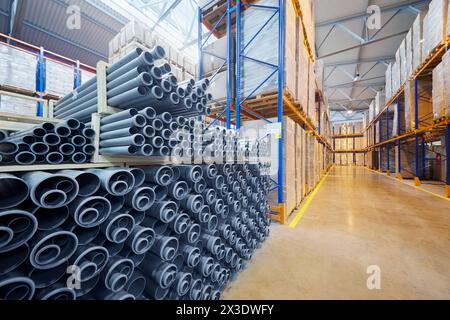 Entrepôt avec des tuyaux en plastique et des boîtes en carton sur des étagères à l'usine. Banque D'Images