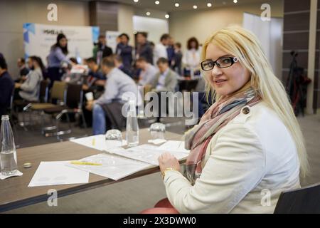 Jeune femme blonde assise à table avec des papiers dans l'auditorium, dof peu profond. Banque D'Images