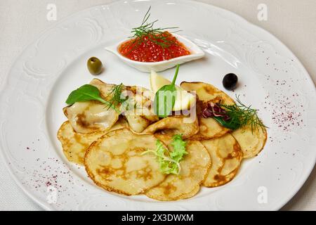 Crêpes de pommes de terre avec légumes verts, olives et caviar rouge. Banque D'Images
