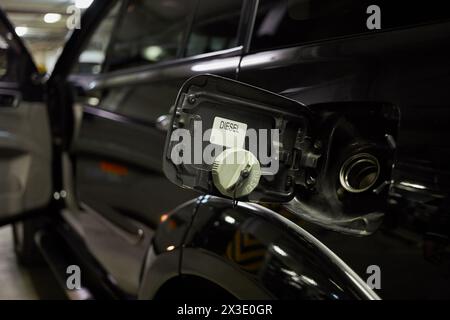 Bouchon de carburant ouvert d'une voiture noire dans un parking souterrain. Banque D'Images