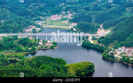 Hefei. 26 avril 2024. Une photo de drone aérien montre un train circulant sur le pont Jianhe le long de la ligne de chemin de fer Chizhou-Huangshan dans la province d'Anhui, dans l'est de la Chine, le 26 avril 2024. Le chemin de fer Chizhou-Huangshan, reliant la ville de Chizhou et la ville de Huangshan, dans la province d'Anhui, dans l'est de la Chine, a commencé à fonctionner vendredi. Il s'agit d'une route touristique reliant la montagne Jiuhua, la montagne Huangshan, le lac Taiping et d'autres attractions touristiques, ce qui est d'une grande importance pour la promotion du développement économique et social le long de la route. Crédit : Liu Yucai/Xinhua/Alamy Live News Banque D'Images