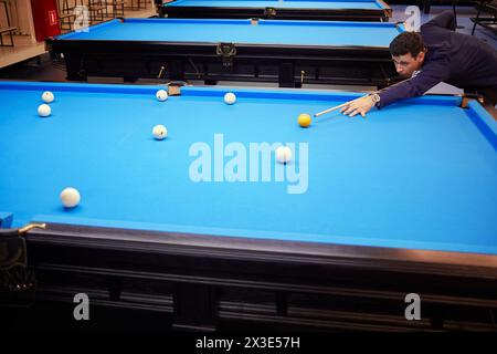 Homme en chemise bleu foncé joue à la pyramide russe dans le club de billard. Banque D'Images