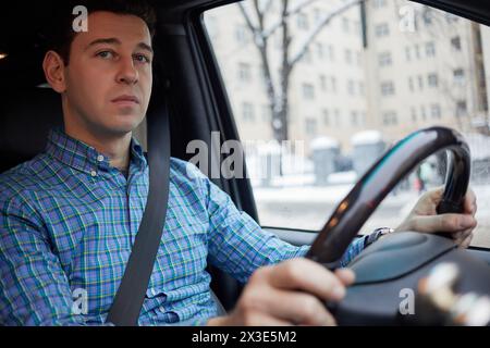 L'homme en chemise à carreaux est assis au volant dans la voiture le jour de whinter. Banque D'Images