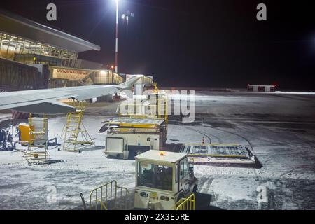 Machines d'aérodrome sous aile d'avion le soir d'hiver. Banque D'Images