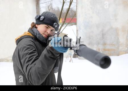 Adolescent avec arme à feu vise pendant le jeu lasertag en plein air le jour d'hiver Banque D'Images