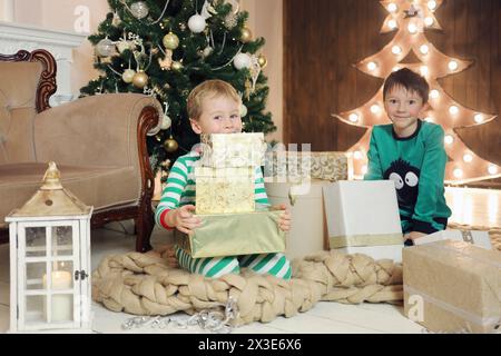 Deux petits garçons avec de nombreux cadeaux dans la chambre avec arbre de noël, se concentrer sur le garçon gauche Banque D'Images