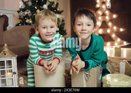 Deux petits garçons avec des cadeaux dans des boîtes sont dans la chambre avec l'arbre de noël, concentrez-vous sur le garçon droit Banque D'Images