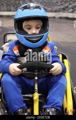 Petit garçon drôle dans le casque se prépare à conduire le kart de compétition Banque D'Images