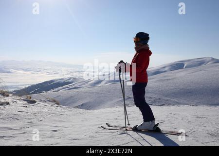 Fille dans les srtands de lunettes de ski sur le sommet de la montagne dans la station de ski le jour d'hiver Banque D'Images