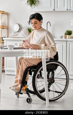 Une femme handicapée en fauteuil roulant travaille à distance depuis sa cuisine, en utilisant un ordinateur portable pour rester connectée et productive. Banque D'Images