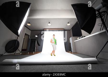 Femme pose dans un studio photo professionnel avec fond blanc, collage Banque D'Images