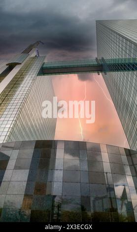 Une image impressionnante où la nature rencontre l'urbanité : la foudre bifurque de façon spectaculaire à travers un ciel orageux, capturé dans le verre réfléchissant des gratte-ciels imposants. Cette juxtaposition des aspirations verticales d’une ville avec la puissance brute des éléments témoigne de la beauté imprévisible des paysages urbains. Réflexion urbaine : gratte-ciel et foudre en façade de verre. Photo de haute qualité Banque D'Images