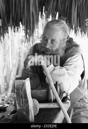 Un homme en tenue coloniale sculpte une statue dans du bois à Saint Augustine, Floride, USA. Cet artisanat traditionnel démontre des techniques artisanales historiques. Banque D'Images