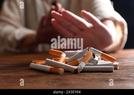 Arrêtez de fumer. Femme faisant un geste d'arrêt à la table en bois, concentrez-vous sur des cigarettes entières et cassées Banque D'Images