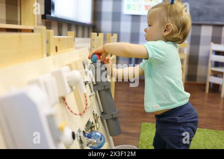 Petite fille joue avec la balle et le conseil occupé dans la maternelle moderne Banque D'Images