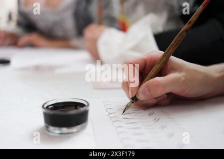 Main féminine écrit par plumes et encre dans un échantillon d'écriture, gros plan Banque D'Images