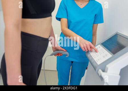 Un praticien de la santé assiste une femme avec un test de composition corporelle à l'aide d'un équipement de pointe. Banque D'Images