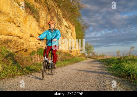 Cycliste masculin chevauchant un vélo pliant sur Steamboat trace, piste cyclable convertie à partir d'un chemin de fer abandonné, près du Pérou, Nebraska, scénographe matinal printanier Banque D'Images