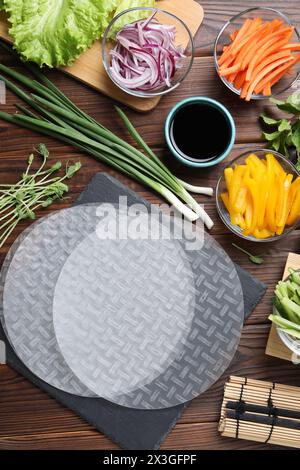 Papier de riz, microgreens et autres ingrédients pour les rouleaux de printemps sur la table en bois, pose à plat Banque D'Images