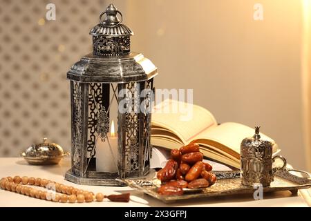 Lanterne arabe, Coran, misbaha et dates sur table blanche Banque D'Images