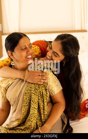 Mère indienne et fille adolescente, embrassant chaleureusement, les deux montrant des sourires joyeux Banque D'Images
