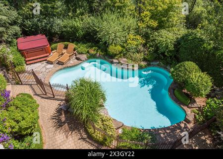 Vue de dessus en piscine entourée de fer forgé couleur cuivre metal clôture de sécurité et diverses plantes vivaces, arbustes et arbres en Banque D'Images