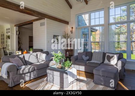 Canapés modèle ektorp rembourrés gris foncé dans le salon avec tapis et parquet en bois de chêne teinté à l'intérieur de la maison de style campagnard, Québec, Canada Banque D'Images