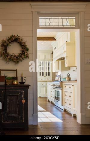 Armoires de style antique en bois d'érable peint blanc avec comptoirs en quartz de couleur beige dans la cuisine avec planches en bois de chêne teinté à l'intérieur du pays Banque D'Images