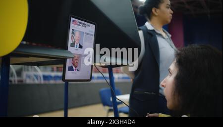 ZAPORIZHYA, UKRAINE -15 MARS 2024 : une femme handicapée physique fait un choix et vote au bureau de vote à l'aide d'une tablette. Races politiques des candidats à la présidentielle américaine. Journée des élections nationales aux États-Unis d'Amérique. Banque D'Images